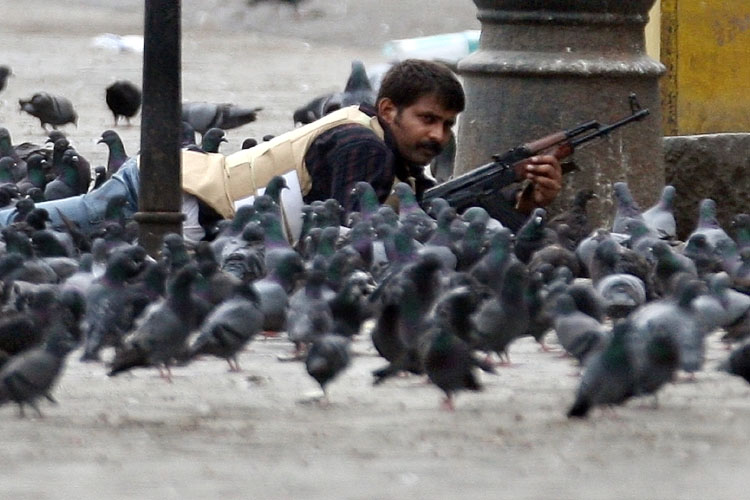 An Indian security force personnel takes position during a heavy exchange of gunfire with terrorists outside the historic Taj Mahal hotel Mumbai on November 28, 2008.  Indian newspapers have slammed the government and intelligence agencies for failing to prevent the Mumbai attacks, saying the country's anti-terrorism forces were ill-prepared for the militants. Up to 130 people were killed and around 300 more wounded in coordinated attacks by gunmen in India's commercial capital Mumbai.    AFP PHOTO/Indranil MUKHERJEE