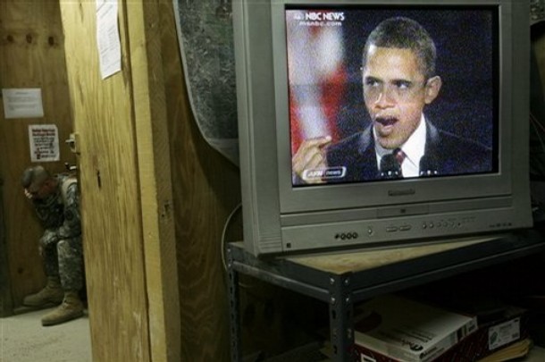 U.S. Army Sgt. Patrick Kopecky, 24, from Manitowoc, WI., left, phones home as a television broadcasts U.S. President-elect Barack Obama's acceptance speech at Forward Operating Base Marez in Mosul, 360 kilometers (225 miles) northwest of Baghdad, Iraq on Tuesday, Nov. 4, 2008. (AP Photo/Maya Alleruzzo)