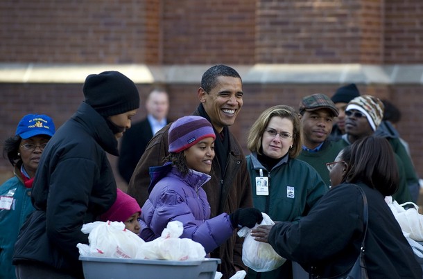 US President elect Barack Obama (C) passes out food at a food bank with his wife Michelle (2nd L) and daughters Malia (3rd L) and Sasha (3rd L) for thanksgiving during a surprise visit to St. Columbanus Parish and School in Chicago, Illinios, November 26, 2008.    AFP PHOTO/Jim WATSON (Photo credit should read JIM WATSON/AFP/Getty Images)