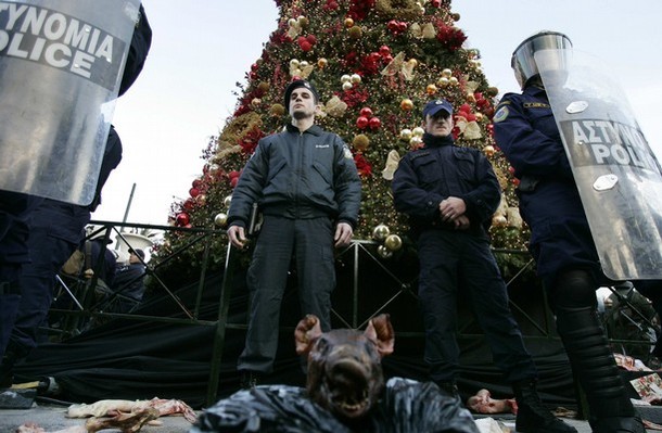 The head of a pig is placed in front of policemen as they stand guard in front of a Christmas tree during a demonstration in Athens December 20, 2008. People protesting over the fatal shooting of a youth in central Athens two weeks ago, threw garbage at the Christmas tree at central Syntagma square.  REUTERS/John Kolesidis   (GREECE)