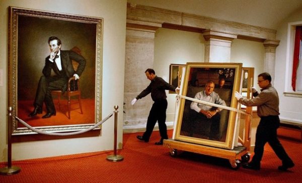 WASHINGTON - DECEMBER 19: National Portrait Gallery Museum Technicians Dale Hunt (L) and Todd Gardner wheel the official portait of U.S. President George W. Bush past the portrait of Abraham Lincolin before hanging it at the gallery December 19, 2008 in Washington, DC. The portrait of Bush was painted by his Yale classmate Robert Anderson of Connecticut. The informal pose was painted from photographs taken at Camp David in April and September of 2008. (Photo by Chip Somodevilla/Getty Images)