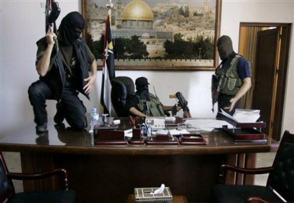 Palestinian militants from Hamas stand at the desk of Palestinian President Mahmoud Abbas inside Abbas' personal office after it was taken over by Hamas in fighting in Gaza City, early Friday, June 15, 2007. Fatah forces collapsed under the onslaught by Hamas, which showed superior organization and motivation. (AP Photo/Hatem Moussa)