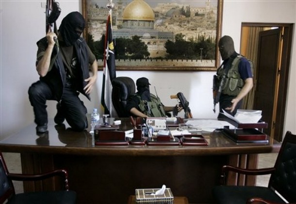 Palestinian militants from Hamas stand at the desk of Palestinian President Mahmoud Abbas inside Abbas' personal office after it was taken over by Hamas in fighting in Gaza City, early Friday, June 15, 2007.  Fatah forces collapsed under the onslaught by Hamas, which showed superior organization and motivation. (AP Photo/Hatem Moussa)