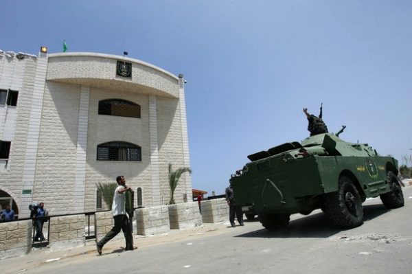 GAZA CITY, GAZA STRIP - JUNE 15: Armed Palestinian Hamas members drive a armoured vehicle seized from Fatah opposition in front of the offices of Palestinian President Mahmoud Abbas on June 15, 2007 in Gaza City, Gaza Strip. After Hamas effectively took over the Gaza Strip on June 14, they now control the police and security and have taken up positions at the Gaza crossings. Palestinian President Mahmoud Abbas dissolved the unity government with Hamas and declared the formation of an emergency government. (Photo by Abid Katib/Getty Images)