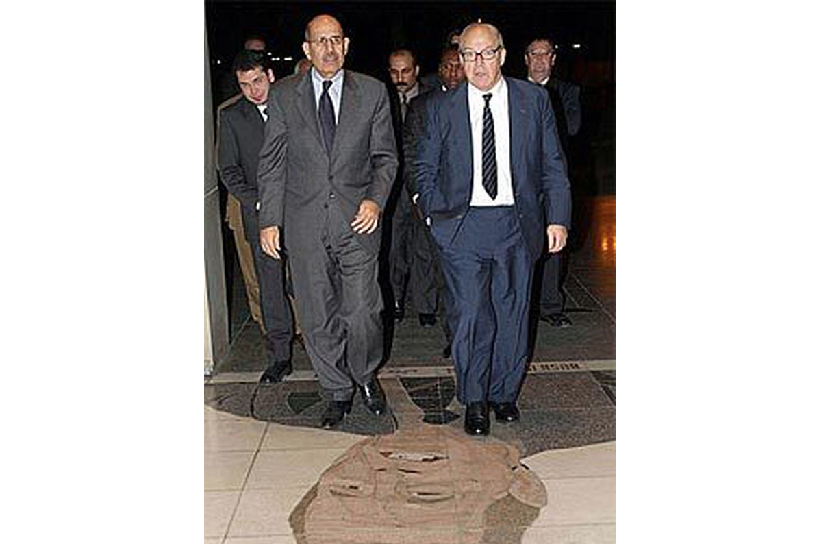 Hans Blix, U.N. Chief Inspector, right, and Mohammed el Baradei, head of the International Atomic Energy Agency, left, walk on a mosaic of former U.S President George Bush at the Al-Rashid Hotel in Baghdad. (AP photo)