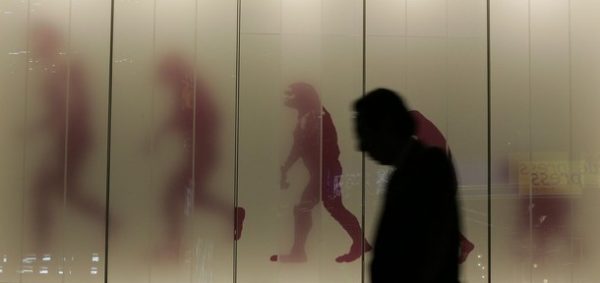 RNPS IMAGES OF THE YEAR 2008 A man walks past a sign showing the evolution of man in a business district in downtown Tokyo November 17, 2008. Japan slid into its first recession in seven years in the third quarter as exports crumbled, and some analysts said an escalation in the global financial crisis may have put the economy on course for its longest ever contraction. REUTERS/Michael Caronna (JAPAN)