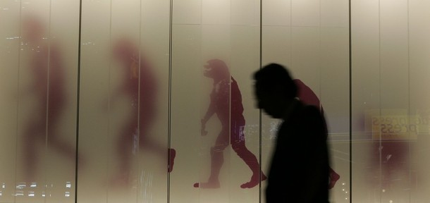 RNPS IMAGES OF THE YEAR 2008  A man walks past a sign showing the evolution of man in a business district in downtown Tokyo November 17, 2008. Japan slid into its first recession in seven years in the third quarter as exports crumbled, and some analysts said an escalation in the global financial crisis may have put the economy on course for its longest ever contraction. REUTERS/Michael Caronna (JAPAN)