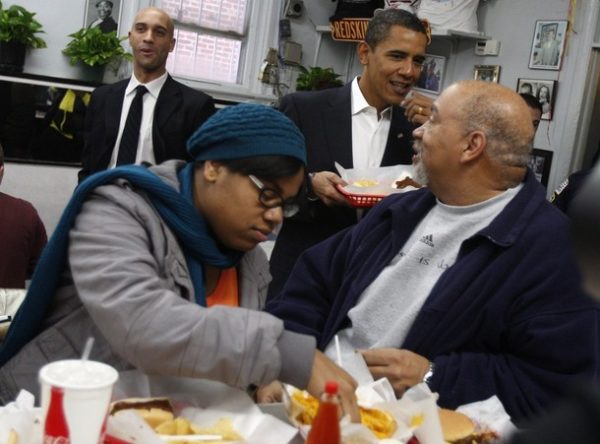 U.S. President-elect Barack Obama (2nd R) picks up his food order at the counter of Ben's Chili Bowl Restaurant during lunch with Washington Mayor Adrian Fenty (L) in Washington, January 10, 2009.     REUTERS/Jim Young    (UNITED STATES)