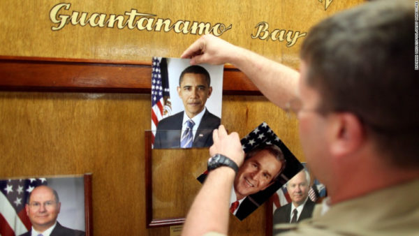 U.S. Navy Chief Petty Officer Bill Mesta replaces an official picture of outgoing President George W. Bush with that of newly- sworn-in U.S. President Barack Obama, in the lobby of the headquarters of the U.S. Naval Base January 20, 2009 in Guantanamo Bay, Cuba.  Bush's eight-year presidency, which has overseen the detention of prisoners at Guantanamo and elsewhere, concluded midday today, and President Barack Obama has said he intends to close the offshore prison and move the trials to U.S. courts. (Photo by Brennan Linsley-Pool/Getty Images) 