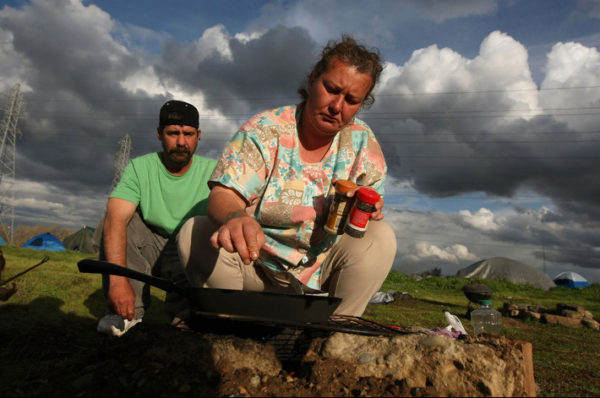 (image: Justin Sullivan/Getty Images. March 4, 2009. caption: Newly homeless couple Tammy Day and her husband Keith Day cook potatoes over a campfire at a homeless tent city in Sacramento, California. The tent city is seeing an increase in population as the economy worsens and more people are becoming unemployed and having their homes slip into foreclosure