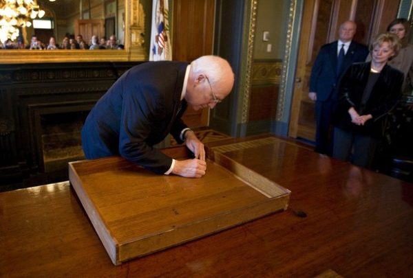 This official White House photograph shows US Vice President Dick Cheney signing the inside of the top drawer of his desk in the Vice President's Ceremonial Office on Monday, January 12, 2009 at the Eisenhower Executive Office Building in Washington, DC. The desk, constructed in 1902 and first used by President Theodore Roosevelt, has been signed by various presidents and vice presidents since the 1940s. Mrs. Lynne Cheney is seen at right. AFP PHOTO / THE WHITE HOUSE / David Bohrer (Photo credit should read DAVID BOHRER/AFP/Getty Images)