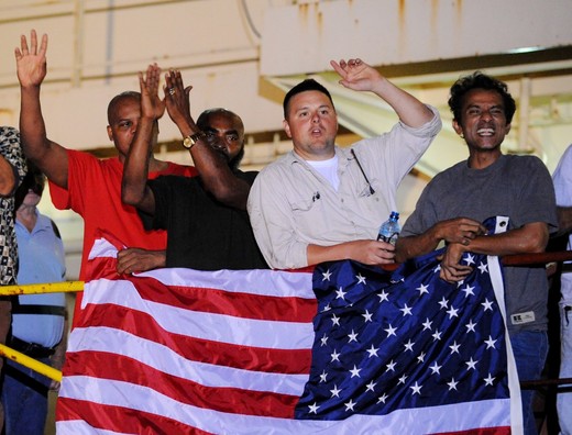 Crew members of the US merchant ship Maersk Alabama gather around a US flag while celebrating that the captain of their ship, Richard Phillips, which had been held captive by the pirates had been freed on April 12, 2009. Somali pirates tried to seize the ship early on April 8, while it was in the Indian Ocean about 500 kilometres (310 miles) off the Somali coast. CNN television, citing a senior US official, reported that three of the four pirates holding Phillips had been killed, and the fourth pirate was in custody. AFP PHOTO/Roberto SCHMIDT (Photo credit should read ROBERTO SCHMIDT/AFP/Getty Images)