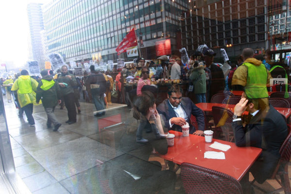 NEW YORK - APRIL 03: White collar workers sit in a coffeeshop as people demonstrate in the financial district April 3, 2009 in New York City. Hundreds of anti-capitalist protesters gathered in the financial district to begin a two- day rally against Wall St. and the recent government bailout of banks and financial institutions. (Photo by Mario Tama/Getty Images)