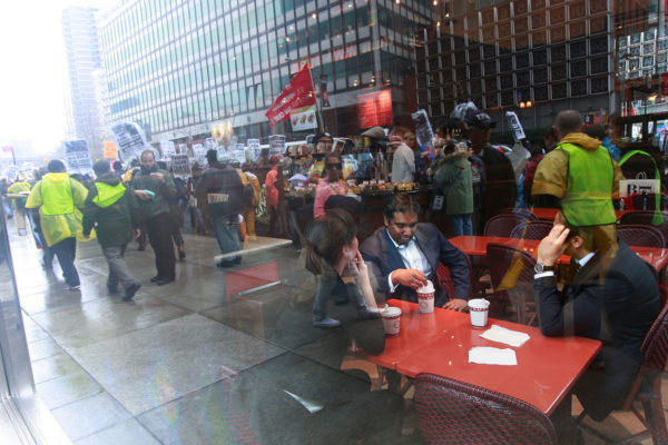 NEW YORK - APRIL 03: White collar workers sit in a coffeeshop as people demonstrate in the financial district April 3, 2009 in New York City. Hundreds of anti-capitalist protesters gathered in the financial district to begin a two- day rally against Wall St. and the recent government bailout of banks and financial institutions.  (Photo by Mario Tama/Getty Images)