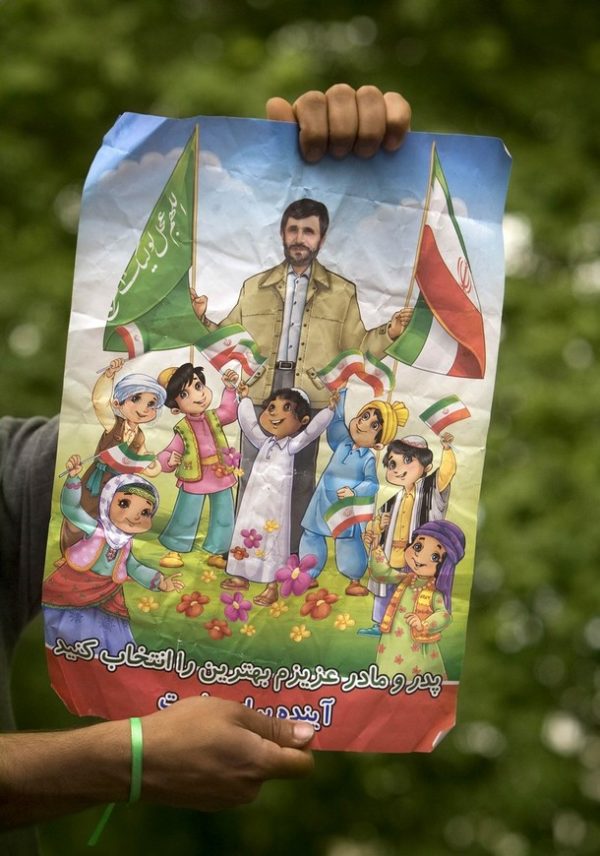 A supporter of former Prime Minister and presidential election candidate Mirhossein Mousavi wears a green ribbon, the symbolic colour of Mousavi's campaign, on his wrist as he holds a campaign poster displaying Iranian President and presidential candidate Mahmoud Ahmadinejad during an election rally in Tehran, June 6, 2009. The words on the poster reads, "Dear father and mother choose the best". REUTERS/Morteza Nikoubazl (IRAN POLITICS ELECTIONS IMAGES OF THE DAY)