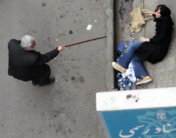 A man with a cane gestures towards a woman on the ground during protests in central Tehran June 14, 2009. Defeated candidate Mirhossein Mousavi demanded Sunday that Iran's presidential election be annulled and urged more protests, while tens of thousands of people hailed the victory of the hardline Mahmoud Ahmadinejad.  REUTERS/Stringer  (IRAN POLITICS ELECTIONS IMAGES OF THE DAY)