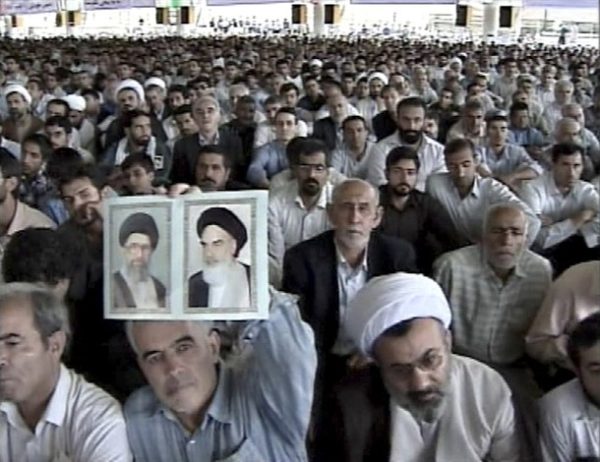 EDITORS' NOTE: Reuters and other foreign media are subject to Iranian restrictions on leaving the office to report, film or take pictures in Tehran.  A man holds photographs of Iran's Supreme Leader Ayatollah Ali Khamenei (L) and the late Ayatollah Ruhollah Khomenei, the father of the 1979 Islamic revolution, as he and others listen to Khamenei's Friday prayer sermon at Tehran University in this video grab June 19, 2009. Khamenei appealed for calm on Friday and attacked "enemies" questioning the result of a presidential vote that has sparked the biggest street protests in the Islamic Republic's history.  REUTERS/IRIB via Reuters TV (IRAN POLITICS ELECTIONS) FOR EDITORIAL USE ONLY. NOT FOR SALE FOR MARKETING OR ADVERTISING CAMPAIGNS. IRAN OUT. NO COMMERCIAL OR EDITORIAL SALES IN IRAN