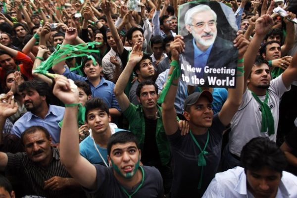 Supporters of the former Prime Minister Mirhossein Mousavi who is a candidate for the upcoming presidential elections react and display his picture as he addresses them at the stadium in the city of Karaj, 50 km (31 miles) west of Tehran June 6, 2009. REUTERS/Damir Sagolj (IRAN POLITICS ELECTIONS)