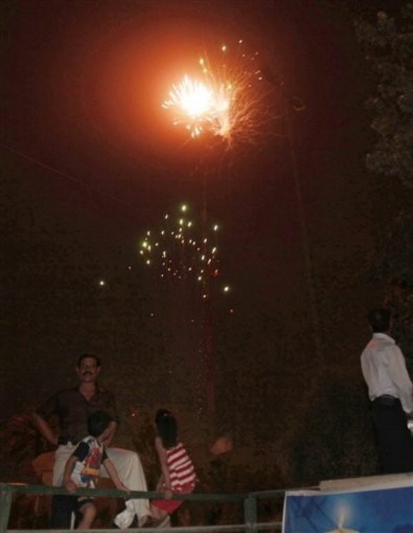 People stand in the dark as they watch fireworks light up the night sky above Baghdad, Iraq, Monday, June 29, 2009. U.S. troops will be out of Iraqi cities by tomorrow Tuesday June 30 in the first step toward winding down the American war effort by the end of 2011. (AP Photo/ Khalid Mohammed)