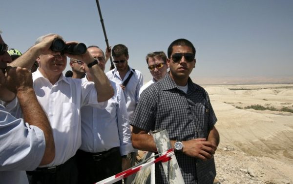 Israel's Prime Minister Benjamin Netanyahu (2nd L) looks through binoculars on a ridge overlooking the Israeli-controlled Allenby Bridge crossing between the West Bank and Jordan July 28, 2009. U.S. envoy George Mitchell and Netanyahu could not agree on a Jewish settlement freeze in talks on Tuesday but said negotiations were advancing. REUTERS/Jim Hollander/Pool (WEST BANK POLITICS)