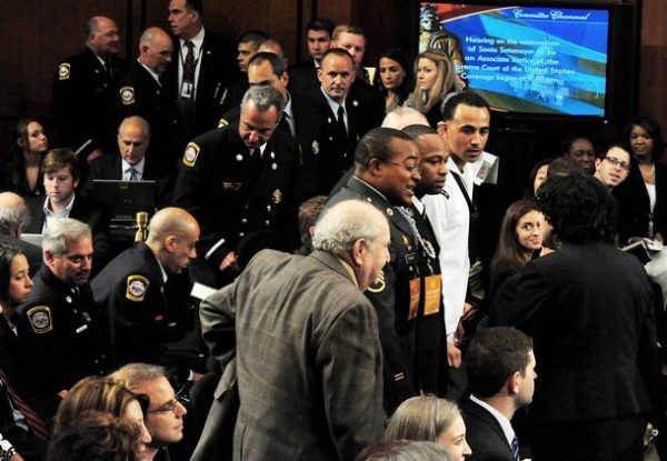 New Haven, Connecticut, firefighters (L) file into the hearing room as US Supreme Court Nominee Sonia Sotomayor (R-back to camera) greets wellwishers on July 15, 2009 before the third day of confirmation hearings before the Senate Judiciary Committee on Capitol Hill in Washington, DC. One ruling likely to draw scrutiny from the US Senate Judiciary Committee tasked with vetting Sortomayor is an affirmative action case in which a mostly-white group of the firefighters alleged discrimination. The US Supreme Court has ruled in favor of the white firefighters, overturning Sotomayor's decision.      AFP PHOTO/Karen BLEIER (Photo credit should read KAREN BLEIER/AFP/Getty Images)