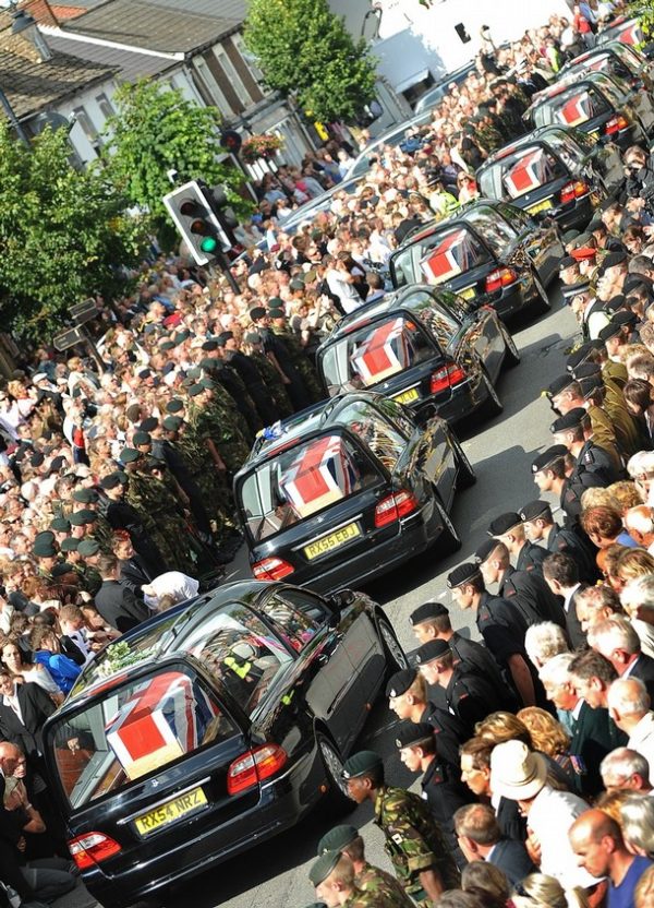 A procession of hearses carrying the bodies of eight British soldiers killed in Afghanistan in a 24 hour period travels through the streets of Wootton Bassett, in Wiltshire, on July 14, 2009. The bodies of eight soldiers killed in Britain's bloodiest 24-hour period in Afghanistan were flown home on Tuesday as the head of the army said they had not died in vain. The families of the men, three of whom were 18-year-olds, were at the RAF Lyneham airbase in southwest England to see the coffins draped in the Union Jack flag carried slowly one by one from the transport plane. Thousands of people, including many soldiers, lined the streets of the nearby town of Wootton Bassett to pay their respects as the eight hearses were driven past, following a private ceremony at a chapel of rest for the families. AFP PHOTO/CARL DE SOUZA (Photo credit should read CARL DE SOUZA/AFP/Getty Images)