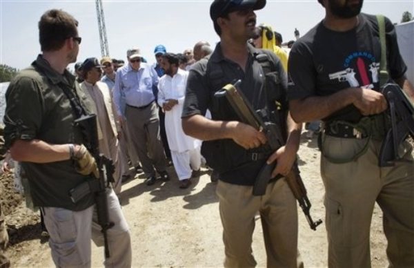 The top U.S. envoy to Pakistan and Afghanistan Richard Holbrooke, in a blue shirt, is escorted by security guards and Pakistani police officers during his visit to a refugee camp in Mardan, northwest Pakistan, Thursday, June 4, 2009. Holbrooke visited Pakistani refugees who have fled fighting between their country's military and Taliban guerrillas and told them Thursday that the United States can't offer them security, but it can offer them aid. (AP Photo/Emilio Morenatti)