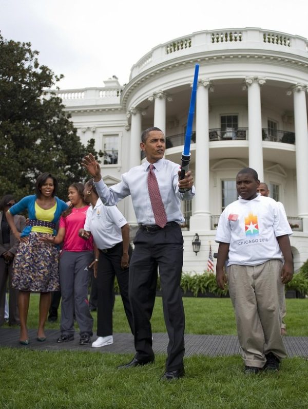 US President Barack Obama (C) pretends to fence with a lightsaber as First Lady Michelle Obama (L) watchs during an event on Olympics, Paralympics and youth sport on the South Lawn of the White House in Washington, DC, September 16, 2009.                   AFP  PHOTO/Jim WATSON (Photo credit should read JIM WATSON/AFP/Getty Images)
