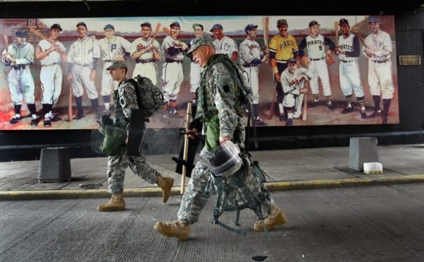 PITTSBURGH - SEPTEMBER 24: National Guardsmen carry riot gear past a mural of Pittsburgh's baseball heroes near the site of the G-20 Summit on September 24, 2009 in downtown Pittsburgh, Pennsylvania. Military forces from Pennsylvania and police from various states were called in to secure the city for the event. President Obama is due to welcome guests this evening for the two-day G-20 summit at Pittsburgh's convention center aimed at promoting global economic growth. (Photo by John Moore/Getty Images)