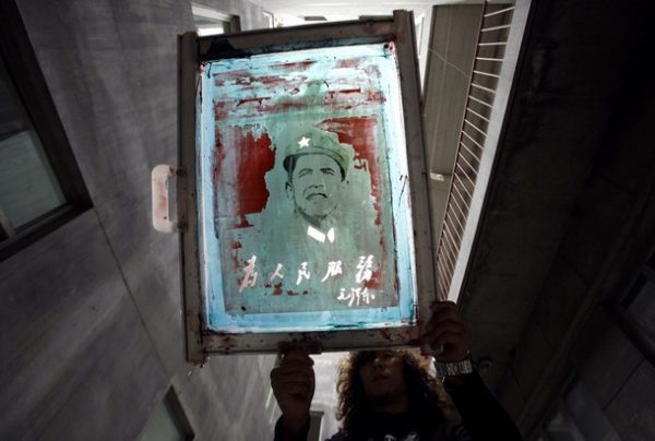 A worker washes ink from a screen print bearing an image of U.S. President Barack Obama's face over that of China's late Chairman Mao Zedong at a shirt printing factory located on the outskirts of Beijing October 30, 2009. The factory currently produces about three thousand shirts bearing the 'Oba Mao' design daily. They are hoping to produce more in time for President Obama's visit to China during mid-November. REUTERS/David Gray  (CHINA SOCIETY POLITICS)
