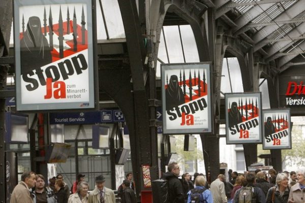 People walk under posters of the Swiss People's Party (SVP) demanding 'Stop - Yes to ban of minarets' at the central station in Zurich October 26, 2009. Switzerland will hold a referendum on banning the construction of new minarets on November 29 after a group of politicians from the SVP and Federal Democratic Union gathered enough signatures last year to force the vote. REUTERS/Arnd Wiegmann (SWITZERLAND POLITICS)