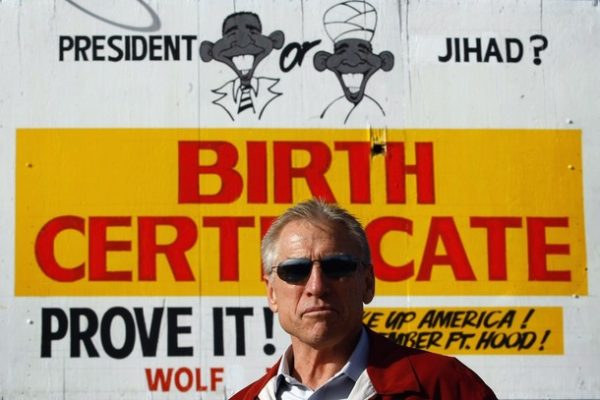 WHEAT RIDGE, CO - NOVEMBER 21:  Phil Wolf, owner of Wolf Automotive used car dealership, stands in front of a billboard on his auto lot on November 21, 2009 in Wheat Ridge, Colorado. Wolf paid $2,500 to have the billboard painted, and it has sparked contraversy since it was put up the day before. Wolf, 57, said the dealership received more than a thousand calls from throughout the U.S. and Canada in a single day, both in support and against the sign. "We've had death threats. We had people call and say they were going to firebomb the place last night," he said, adding that local police provided overnight security outside the dealership because of the threats. Wolf, a supporter of the "birther" movement, questions President Obama's citizenship. "We've got to recall our country, the election," he said. This guy (Obama), is illegal." He also blamed the President for the massacre at Ft. Hood. "The cavalier attitute taken by Mr. Obama towards the enemy within us is absolutely horrible. If I had a snake in the house, I would kill it," Wolf said. Several left-leaning advocacy groups have called on the public to boycott the auto dealership. (Photo by John Moore/Getty Images)