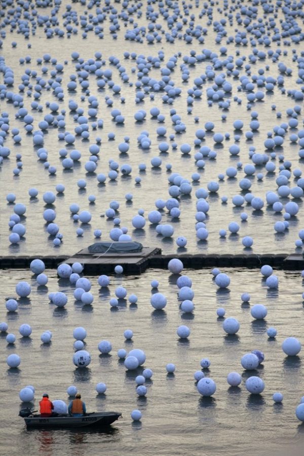 Workers arrange "wishing spheres" from a boat as part of an art installation on the Singapore River December 18, 2009. People pen their New Year wishes on these wishing spheres throughout December to be placed on the river as part of the coming New Year Day celebrations. REUTERS/Edgar Su (SINGAPORE - Tags: SOCIETY)