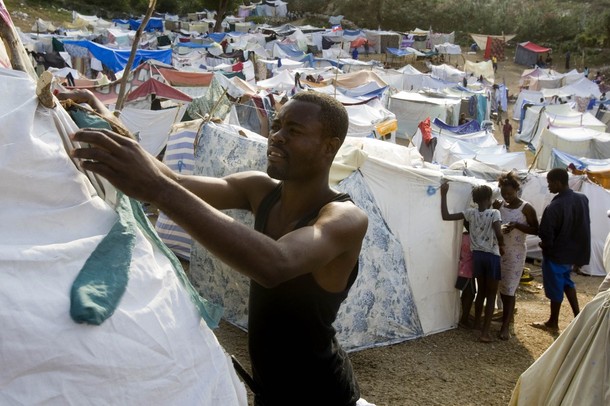 A man sets up a tent in a makeshift camp at a golf course in Port-au-Prince