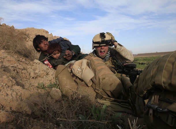 A U.S. Marine from Bravo Company, 1st Battalion, 6th Marines, gestures as he tries to protect an Afghan man and his child after Taliban fighters opened fire in the town of Marjah, in Nad Ali district, Helmand province, February 13, 2010. U.S.-led NATO troops launched a crucial offensive on Saturday against the Taliban's last big stronghold in Afghanistan's most violent province and were quickly thrown into a firefight with the militants. REUTERS/Goran Tomasevic  (AFGHANISTAN - Tags: CIVIL UNREST POLITICS CONFLICT IMAGES OF THE DAY)
