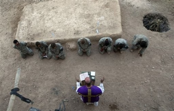 U.S. soldiers of the 1st Battalion, 17th Infantry Regiment, 5th Brigade, 2nd Infantry Division, kneel as father Carl Subler, U.S. Cpt. Chaplain from Versailles, Ohio, celebrates a mass service in an outpost in the Badula Qulp area, West of Lashkar Gah in Helmand province, southern Afghanistan, Sunday, Feb. 21, 2010. (AP Photo/Pier Paolo Cito)