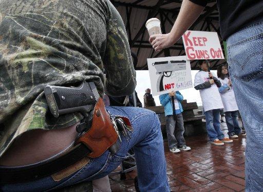 (photo: Elaine Thompson/A.P. caption: Greg Dement, left, is handed a Starbucks coffee drink as he sits with a handgun strapped to his belt while looking on at an anti-gun rally in Seattle, Wednesday, March 3, 2010. Starbucks is sticking to its policy of letting customers carry guns where it is legal and said it does not want to be put in the middle of a larger gun-control debate.)