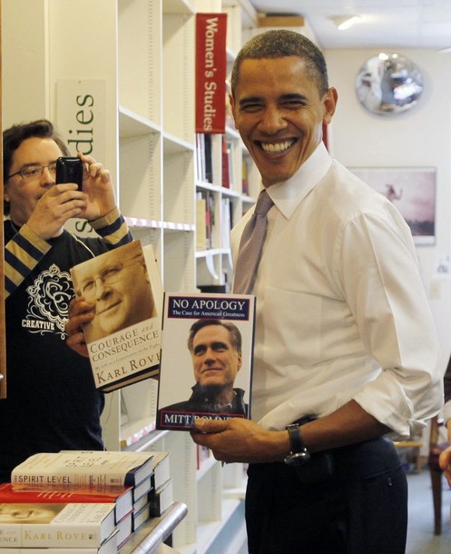 U.S. President Barack Obama holds up books by former Republican presidential candidate Mitt Romney and President George W. Bush's political strategist Karl Rove (L) as he shops for books for his daughters Sasha and Malia at Prairie Lights book store in Iowa City, March 25, 2010. REUTERS/Jason Reed (UNITED STATES - Tags: POLITICS)