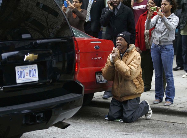 A man gets on his knees next to the car carrying U.S. President Barack Obama as he pulls away from Valois restaurant in Chicago, October 31, 2010.   REUTERS/Larry Downing (UNITED STATES - Tags: POLITICS)