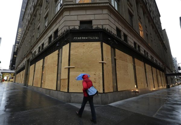 TOPSHOTS A woman walks past a boarded up Saks Fifth Avenue  October 29, 2012 as New Yorkers prepare for Hurricane Sandy which is suppose to hit the city later tonight. Much of the eastern United States was in lockdown mode October 29, 2012 awaiting the arrival of a hurricane dubbed "Frankenstorm" that threatened to wreak havoc on the area with storm surges, driving rain and devastating winds.  AFP PHOTO / TIMOTHY A. CLARY