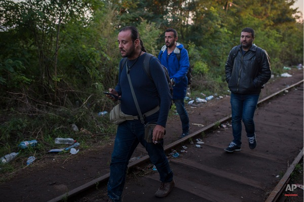 In this Saturday, Sept. 12, 2015 photo, Mohammed al-Haj, center, with his friends Dr. Mohanad Abdul-Qader, left, and Dr. Ahmed Naasan try to pass from the Serbian village of Horgos to Hungary.