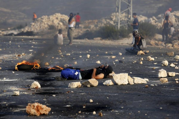 A Palestinian rests during clashes with the Israeli army near the Jewish settlement of Bet El, near the occupied West Bank city of Ramallah, Oct. 5, 2015. A Palestinian teenager was killed on Monday in a clash with Israeli soldiers near the West Bank town of Bethlehem, a Palestinian hospital source said. Violence in the Israeli-occupied West Bank and Jerusalem has intensified in the past few weeks and the teenager's reported death was the latest in a series of incidents that has raised fears of wider escalation.