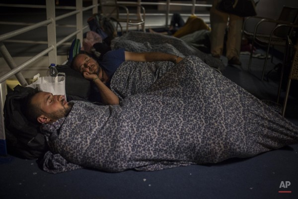 Mohammed al-Haj, foreground, and his friend Dr. Mohanad Abdul-Qader, also from Syria, sleep on the deck of a ferry in this photo taken on Wednesday, Sept. 9, 2015, as they travel from Lesbos to Athens. Ferry officials barred the refugees from entering the lounges on the lower decks, where tourists and Greeks stretched out on comfortable seats. Instead, the migrants were told to cram on the eighth level, but when the smell there became too much, Mohammed and others slept on the open-air deck, exposed to the cold night breeze and the rain. “Of course, this is a kind of racism. They look at us Syrians as animals,” Mohammed said. (AP Photo/Santi Palacios)