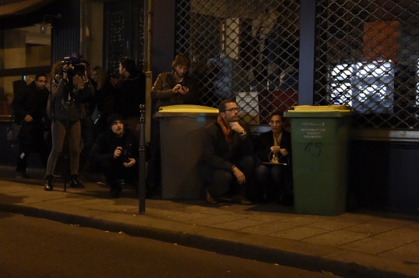 Journalists take cover near the Bataclan concert hall in central Paris, on November 13, 2015. A number of people were killed and others injured in a series of gun attacks across Paris, as well as explosions outside the national stadium where France was hosting Germany. AFP PHOTO / DOMINIQUE FAGET (Photo credit should read DOMINIQUE FAGET/AFP/Getty Images)