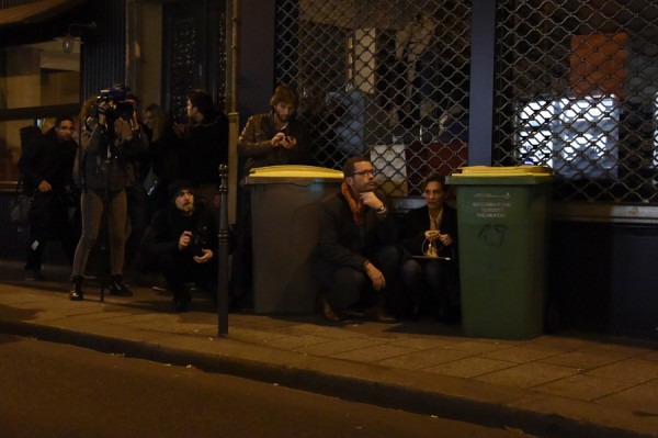 Journalists take cover near the Bataclan concert hall in central Paris, on November 13, 2015. A number of people were killed and others injured in a series of gun attacks across Paris, as well as explosions outside the national stadium where France was hosting Germany. AFP PHOTO / DOMINIQUE FAGET (Photo credit should read DOMINIQUE FAGET/AFP/Getty Images)