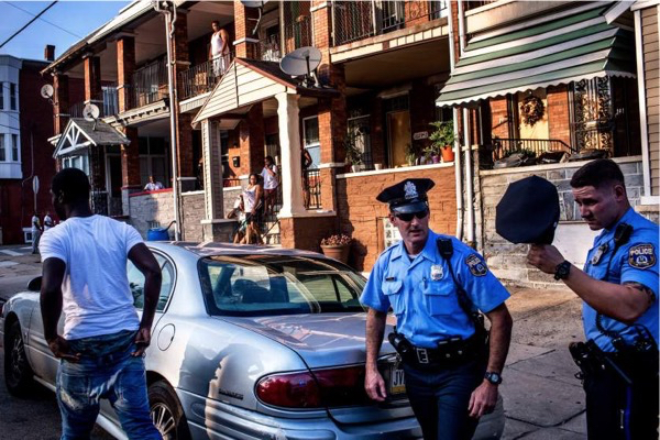 Officers Paul Watson, right, and his partner Officer Richard O'Brien make a traffic stop as neighbors look on. After the police searched his car, the man was released. July 29, 2015. Philadelphia, Pa.