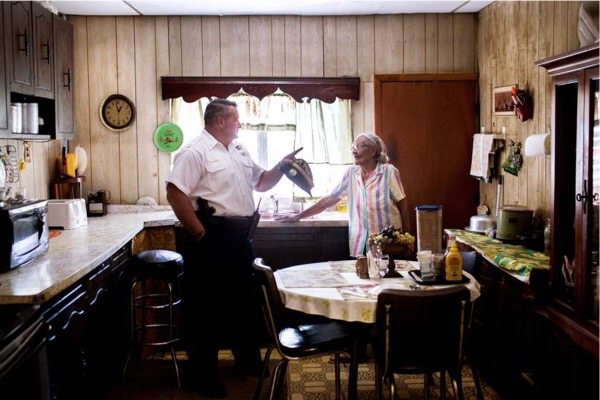 Captain Joe Bologna chats with Louise Robinson in her kitchen after she called him in off the street to look at a problem with overgrowth and vermine in the unkempt garden of an abandoned house behind her home. Robinson has lived in her home down the street from the 19th District station since the '50s, and says that hers was one of the first black families to move to the neighborhood. July 31, 2015. Philadelphia, Pa. Natalie Keyssar for TIME.