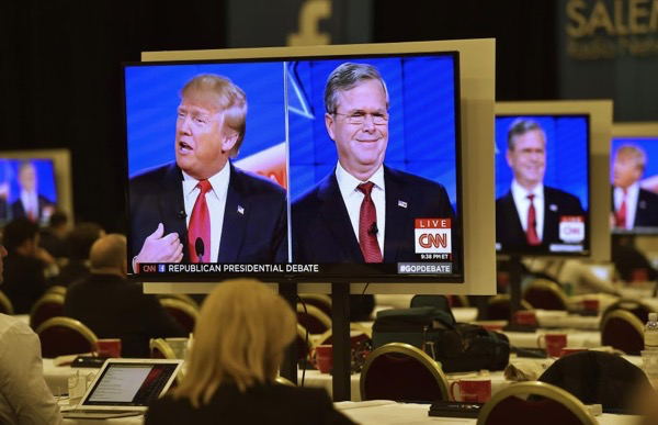 Donald Trump and Jeb Bush are seen debating on video monitors in the press room during the GOP debate.