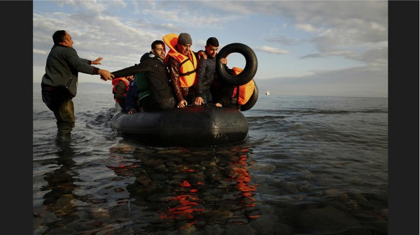 Refugees arrive, some not wearing life jackets, after crossing the Aegean Sea. A volunteer encourages this group to remain calm as they arrive at the shore of Lesbos on Nov. 10.