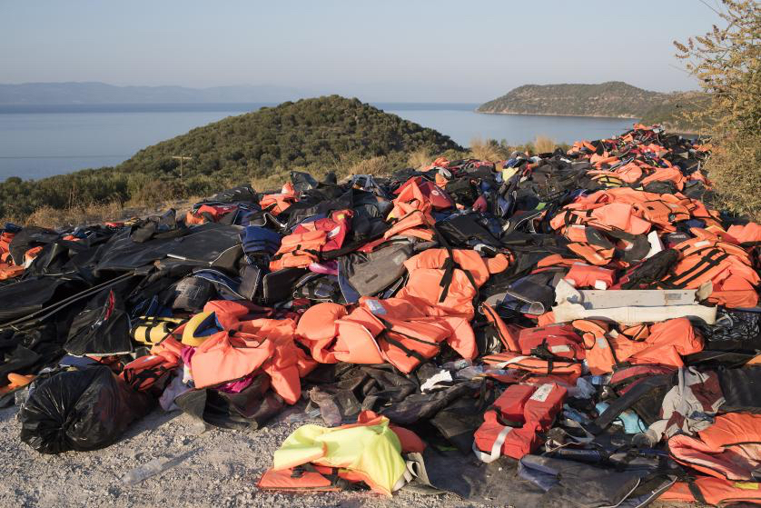 Yuri Kozyrev—NOOR for TIME. caption: A beach on the Greek island of Lesbos is festooned with orange life jackets and deflated rafts abandoned by migrants who are coming ashore near the village of Skala Sikamineas after navigating the 6-mile crossing from Turkey on inflatable rafts. Between 2,000 and 3,500 migrants now reach the island daily, riding on about 100 inflatable rafts. Sept., 2015.